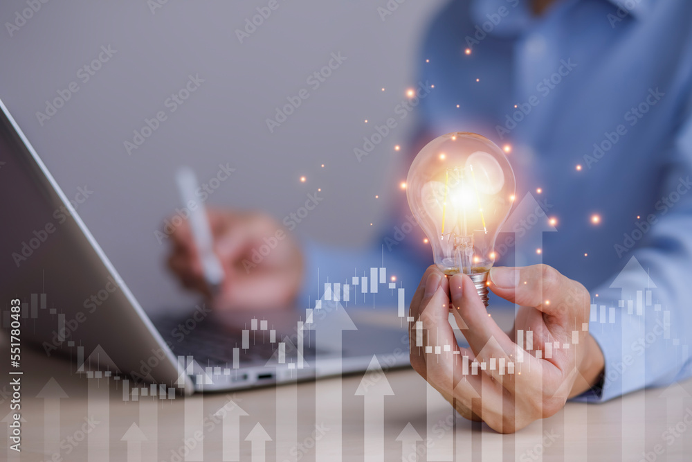 Businessman hand holding light bulb with icons and working on the desk, Creativity and innovation ar