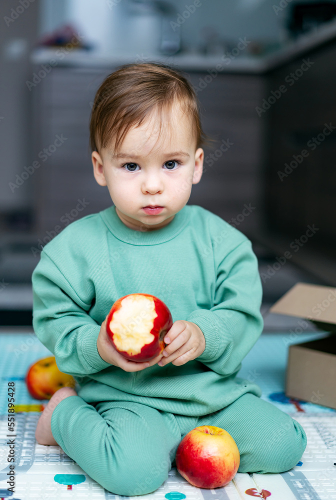 可爱的男婴在家吃苹果。健康的儿童营养