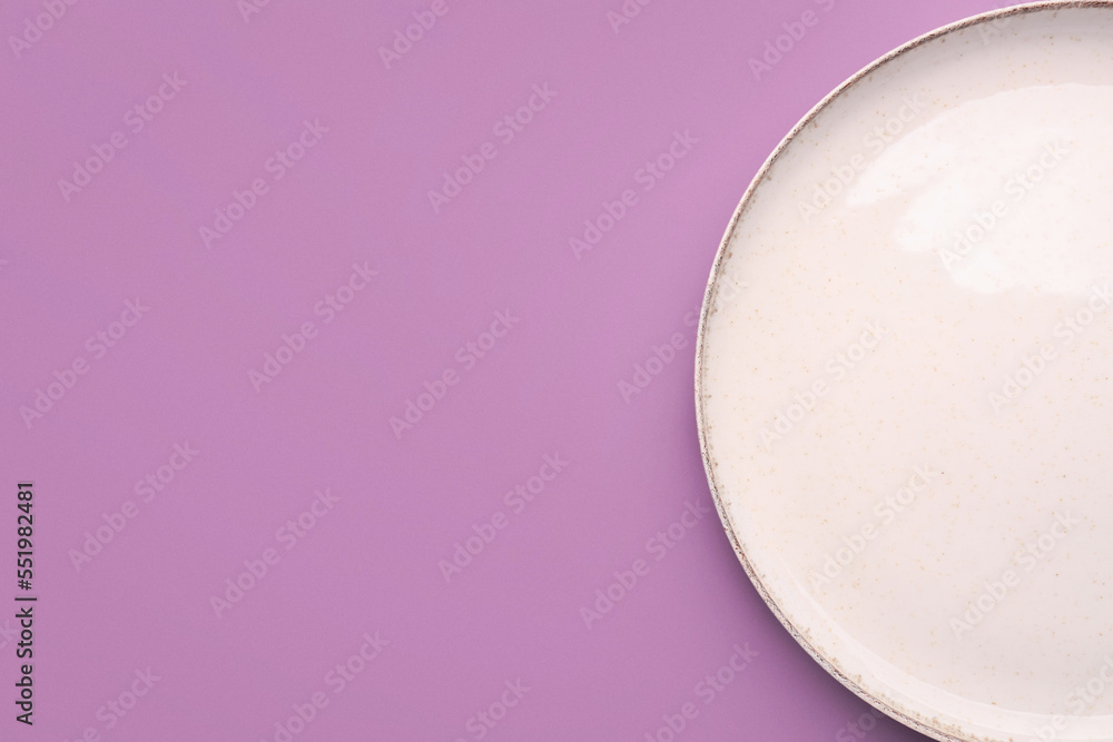 White plate on lilac background, top view