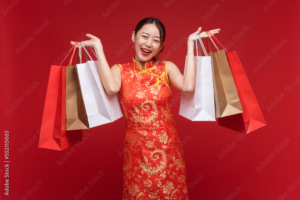 年轻的亚洲女性穿着红色背景的红色购物袋，为中国新年做准备