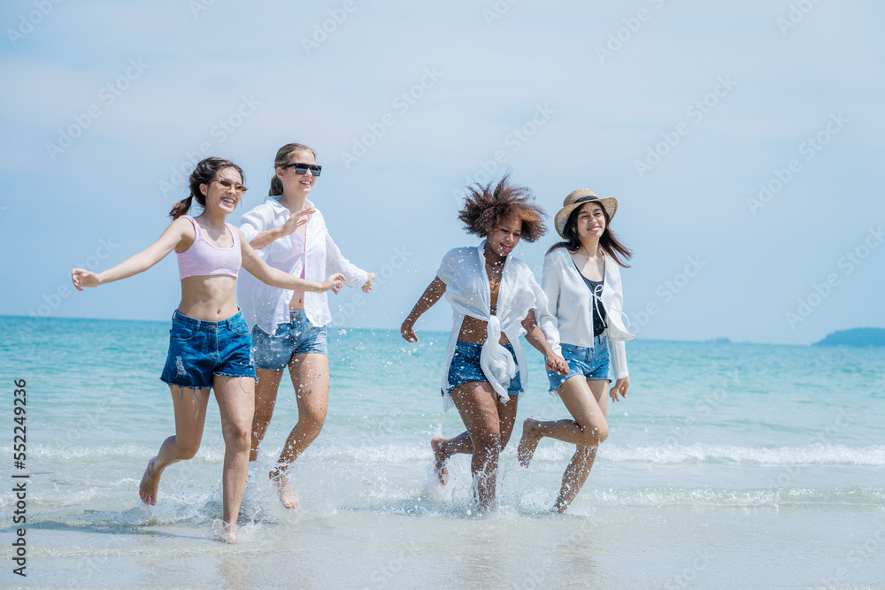 阳光明媚的日子里，年轻的女人和朋友们在海滩上玩耍，快乐的朋友们一起在海滩上。