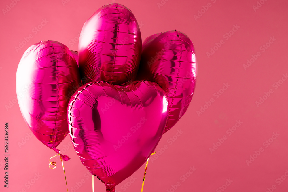 四个闪亮的粉红色心形气球漂浮在粉红色背景上，带有复制空间