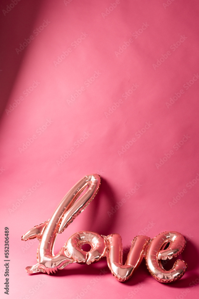 粉红色背景上带有复制空间的金属淡粉色爱情文本气球的垂直