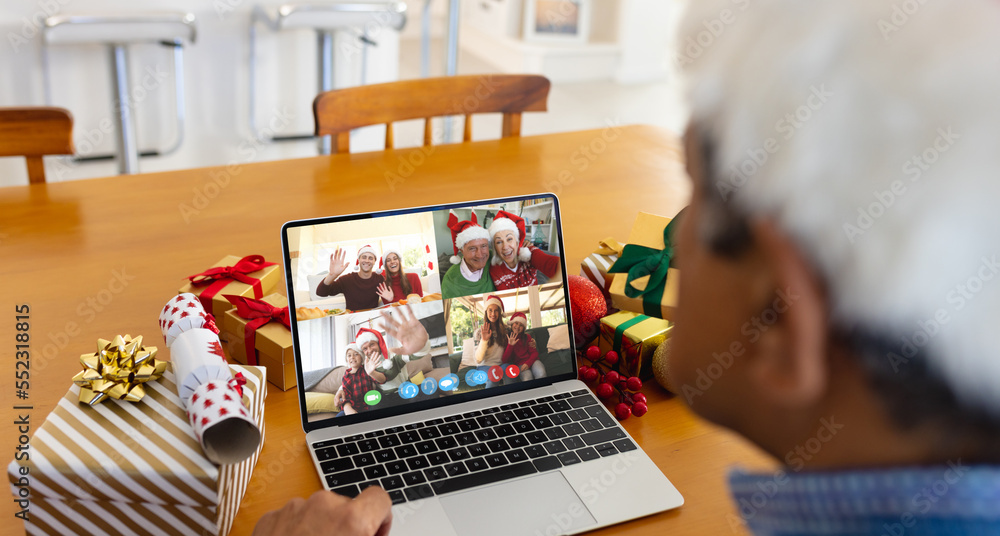 Senior biracial man having christmas video call with diverse people