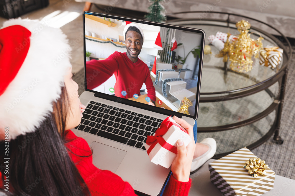 Caucasian woman having christmas video call with african american man