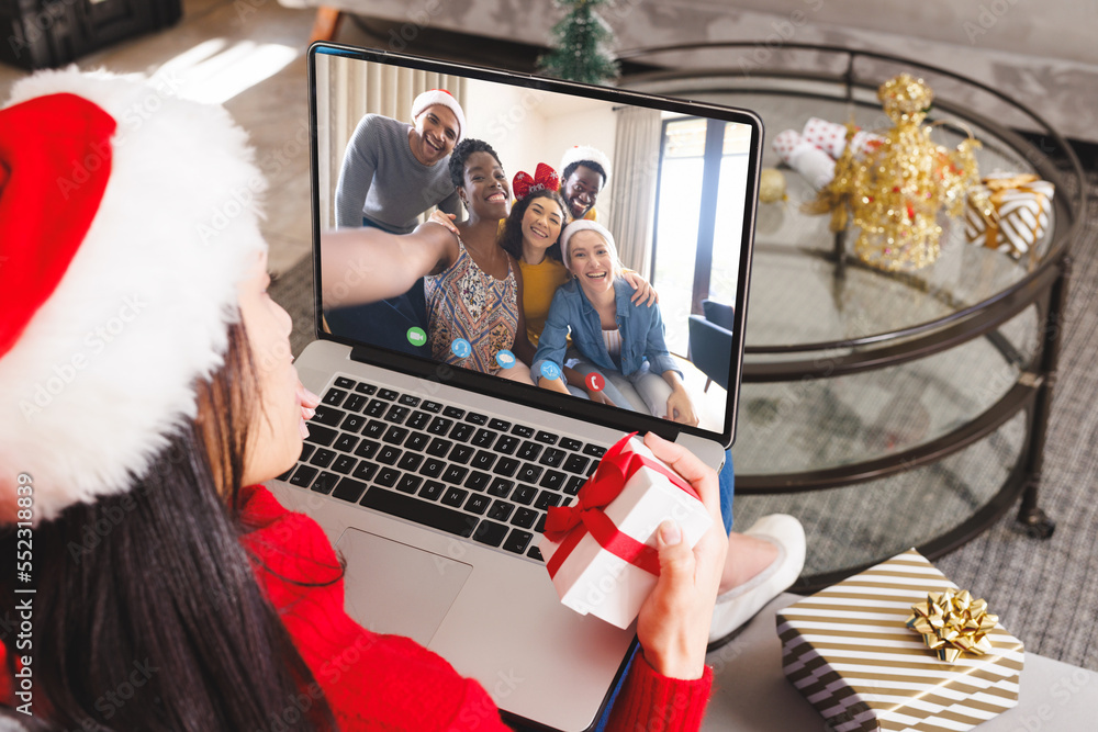 Caucasian woman having christmas video call with diverse people