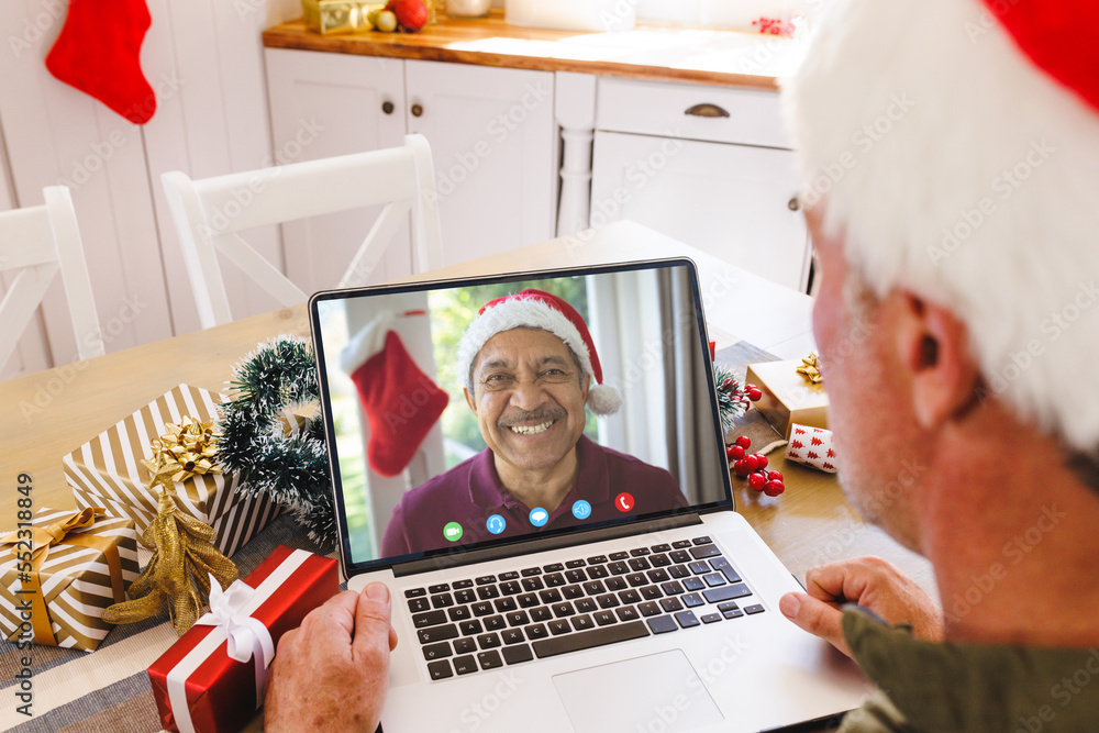 Senior caucasian man having christmas video call with senior biracial man