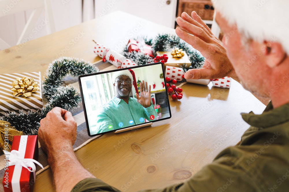 Senior caucasian man having christmas video call with senior african american man