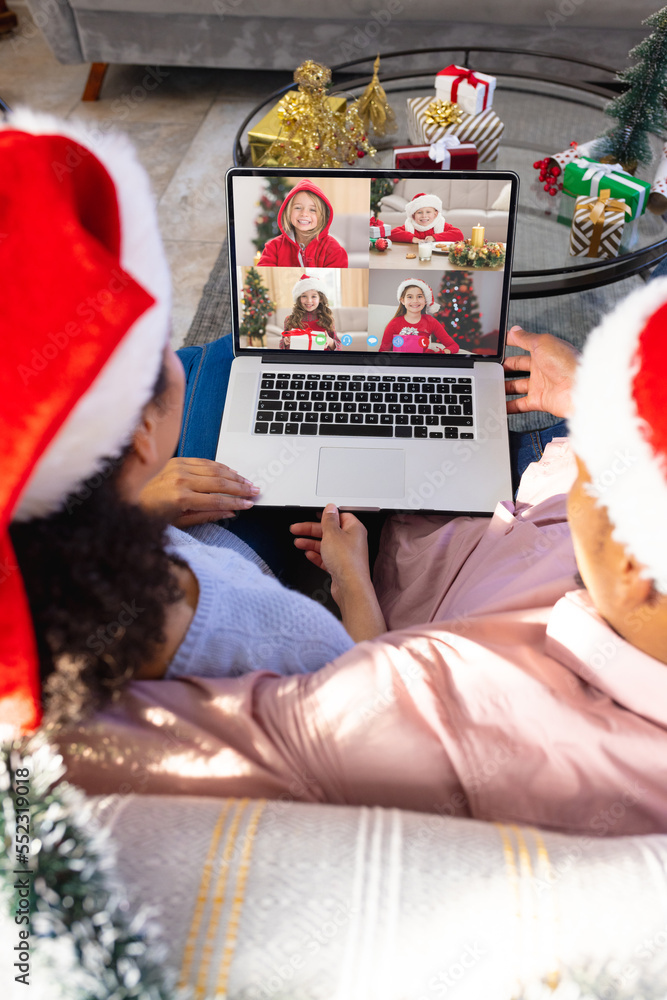 African american couple having christmas video call with diverse children