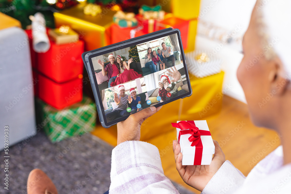 African american woman having christmas video call with diverse people