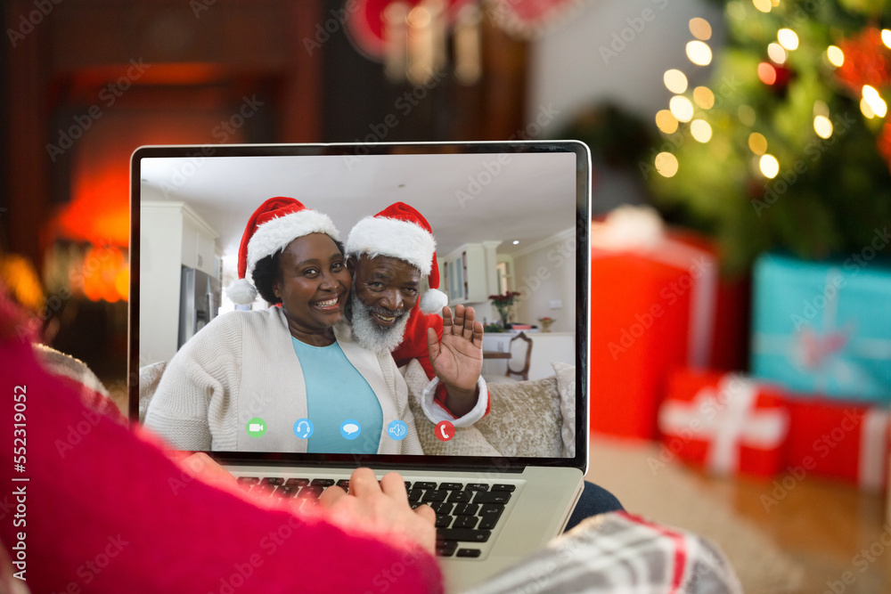 Caucasian woman having christmas video call with senior african american couple
