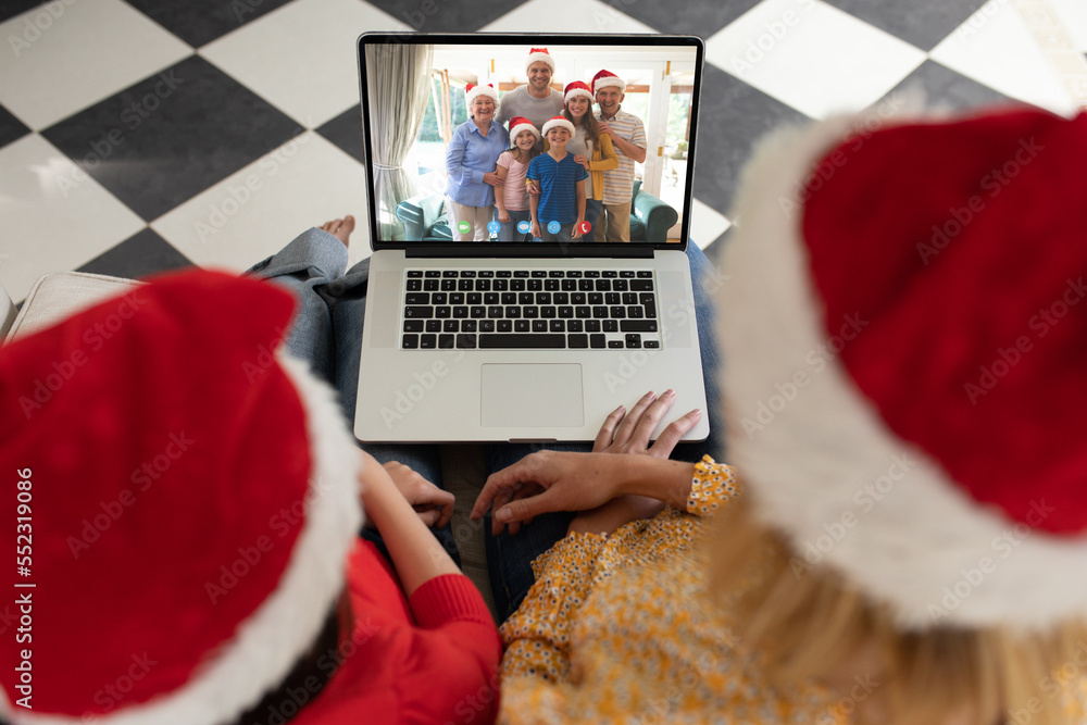 戴着圣诞老人帽的高加索母女在圣诞笔记本电脑上与高加索家庭视频通话