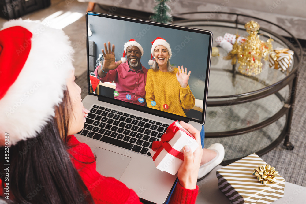戴着圣诞老人帽的白人妇女与一对幸福的多元化夫妇进行视频通话
