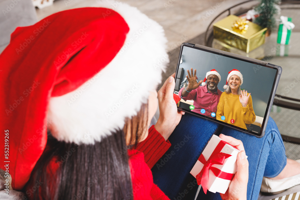 戴着圣诞老人帽的白人妇女与一对幸福的多元化夫妇进行视频通话