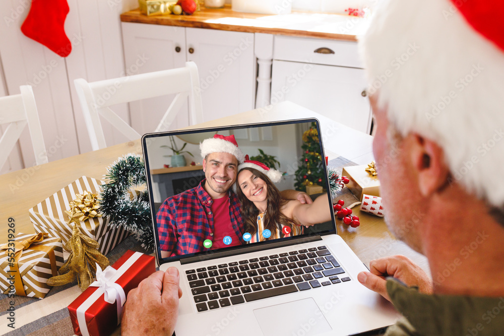 戴着圣诞老人帽的白人男子与幸福的白人夫妇视频通话
