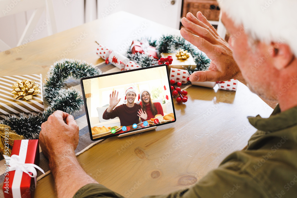 Caucasian man with santa hat having video call with happy caucasian couple