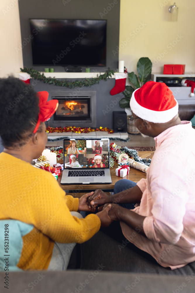 戴着圣诞老人帽的非裔美国夫妇与快乐的高加索朋友进行视频通话