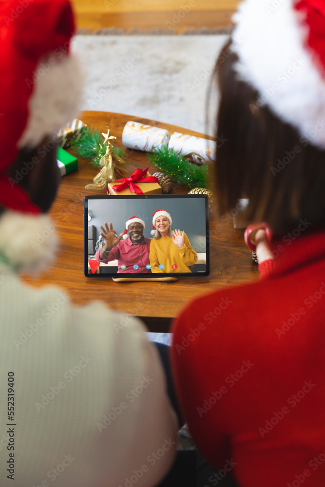 戴着圣诞装饰品的多元化夫妇与快乐的多元化夫妇进行视频通话