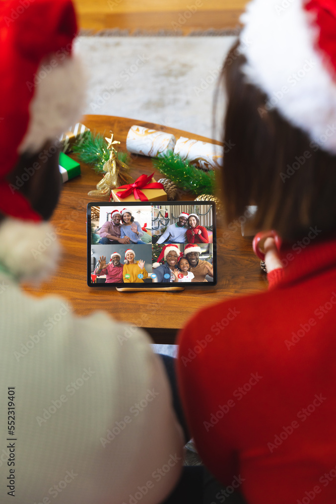 Diverse couple with christmas decorations having video call with happy diverse friends