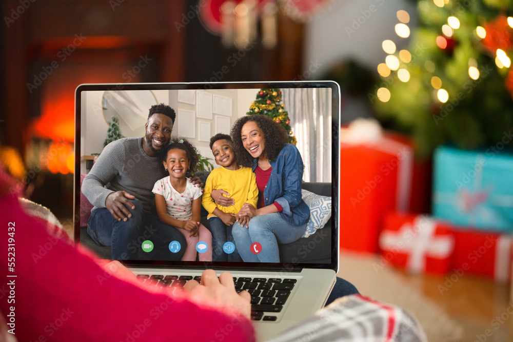 Caucasian woman with christmas decorations having video call with happy african american family