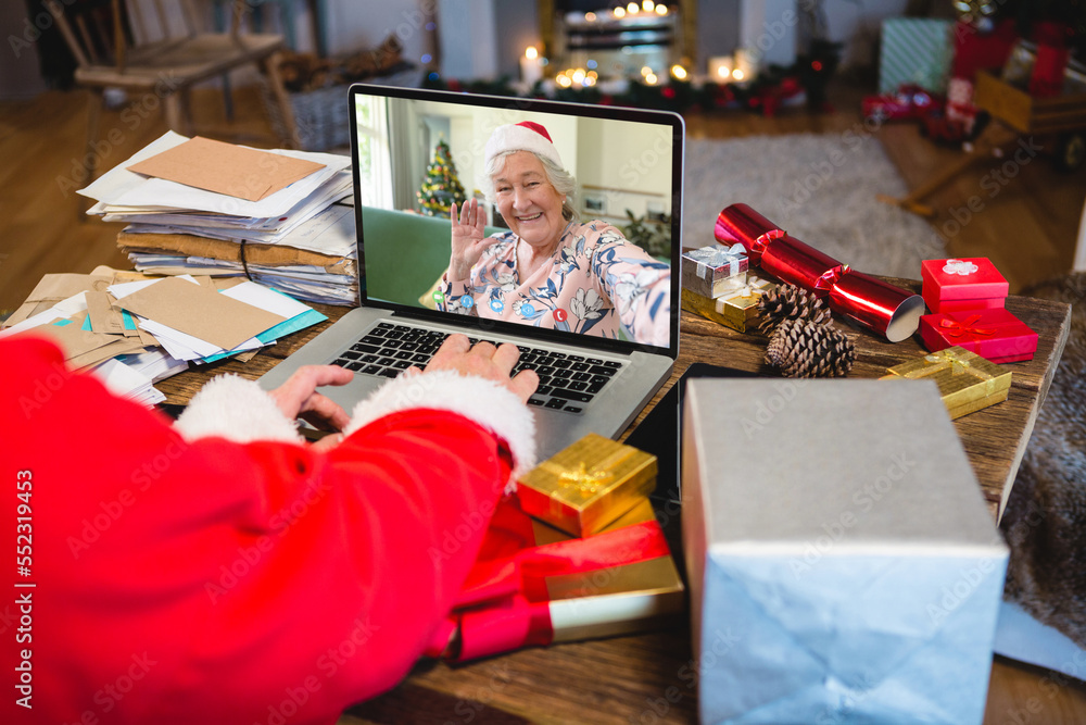 圣诞老人带着圣诞礼物与快乐的白人高级女性视频通话