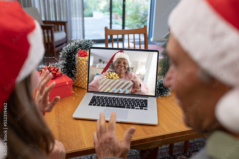 戴着圣诞老人帽的白人父女与快乐的非裔美国妇女视频通话