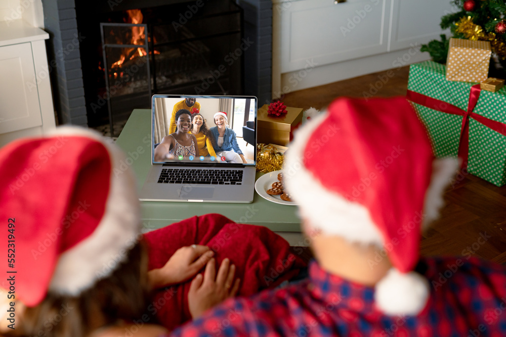 Caucasian couple with santa hats having video call with happy diverse friends