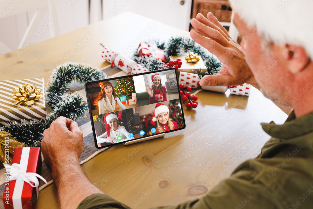 Caucasian man with santa hat having video call with happy caucasian friends