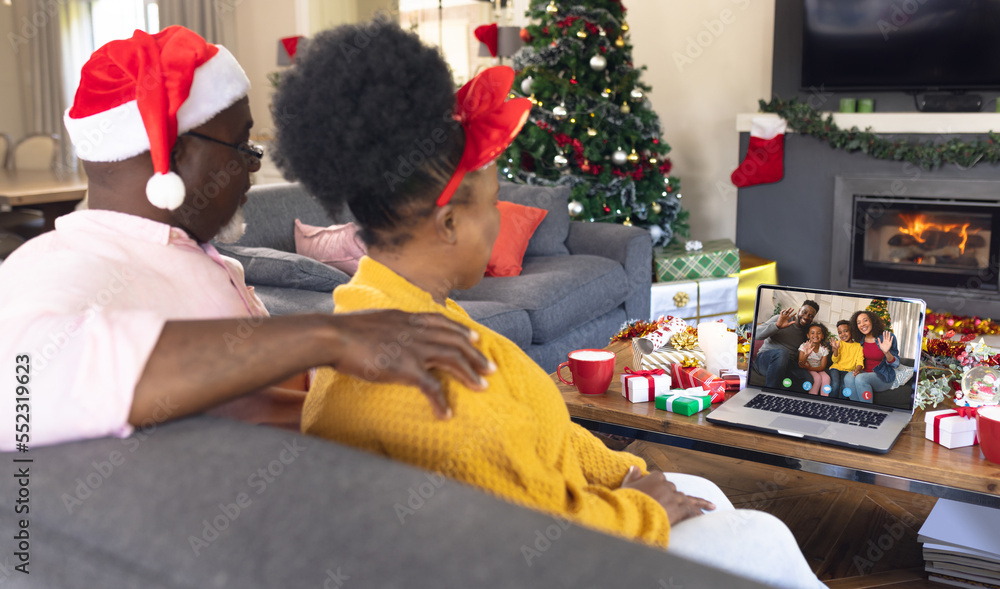 African american couple with santa hats having video call with happy african american family
