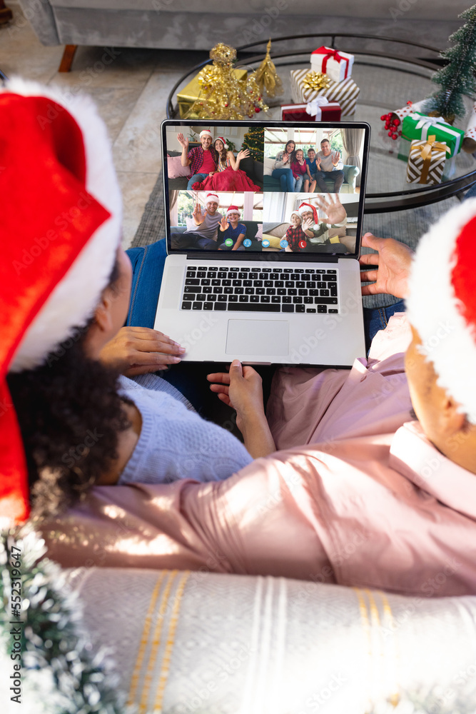 戴着圣诞老人帽的混血夫妇与快乐的高加索朋友视频通话
