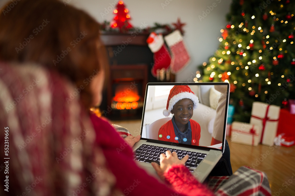 Caucasian woman with christmas decorations having video call with happy african american boy