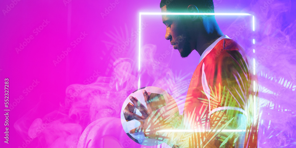 非洲裔美国男子足球运动员，拿着球站在发光的植物和广场旁