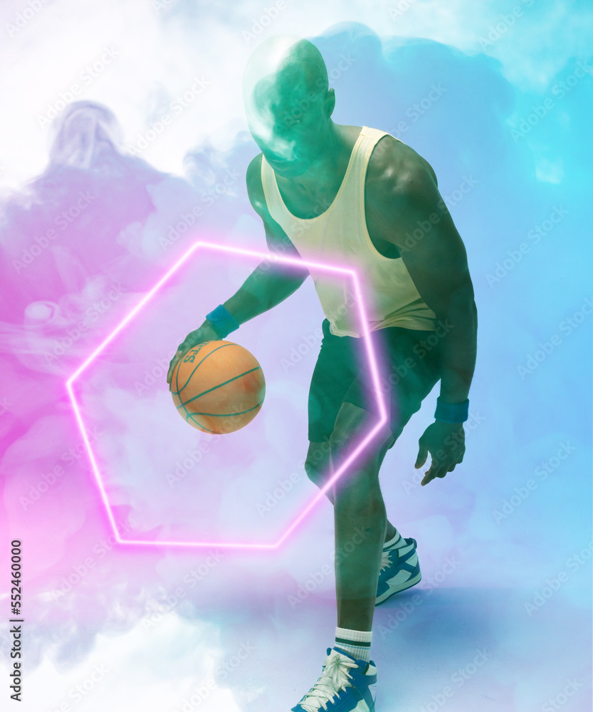 African american male player dribbling basketball by illuminated hexagon on blue smoky background