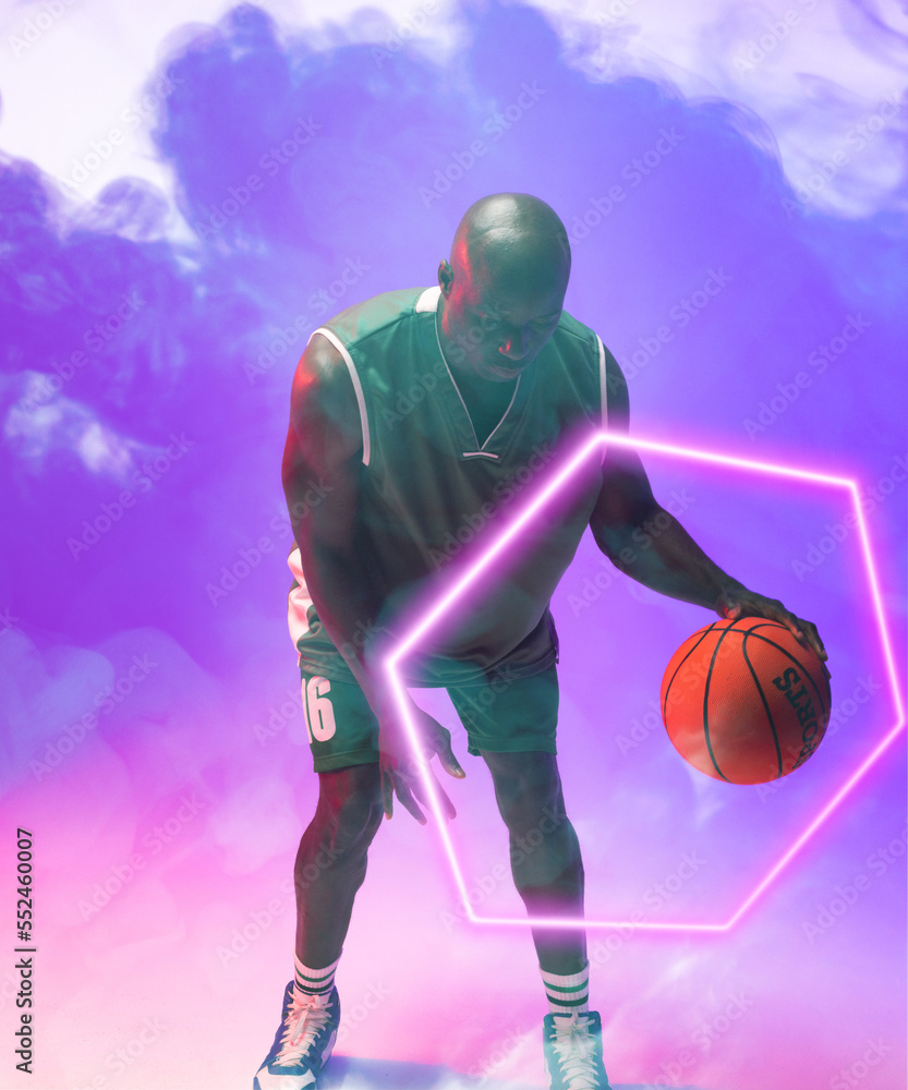 African american male basketball player dribbling ball by illuminated hexagon on smoky background