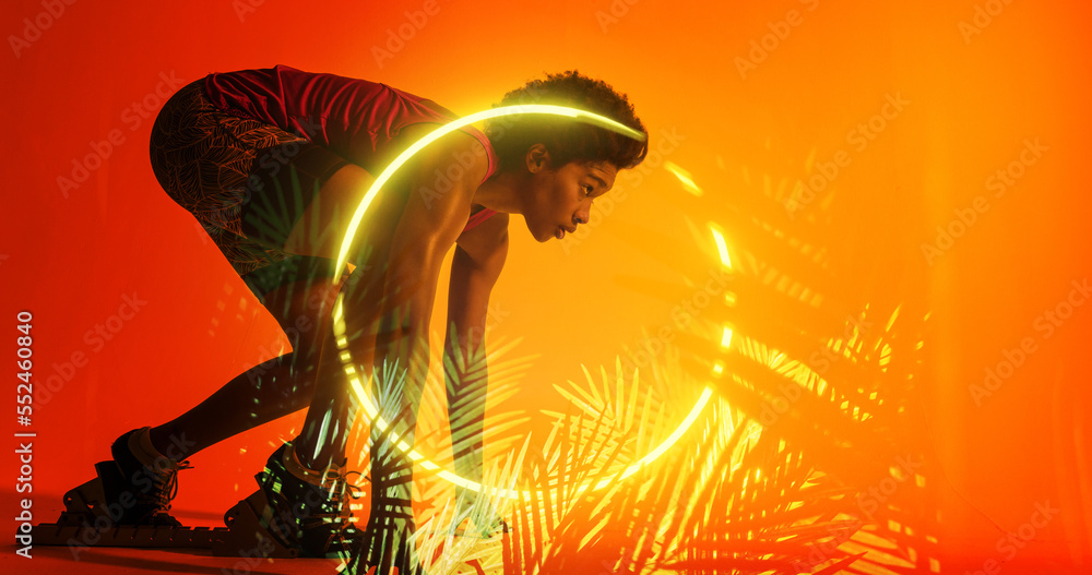 Side view of biracial female athlete at starting position by illuminated plants and circle