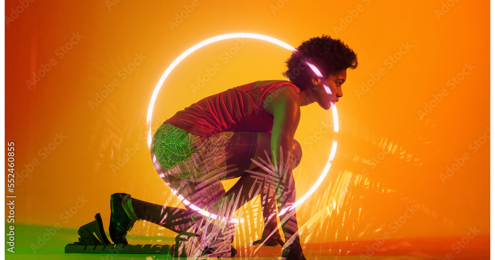 Biracial female athlete crouching at starting position by illuminated plants and circle, copy space