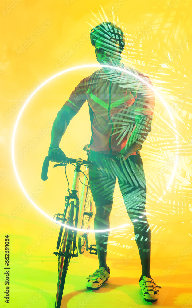 非裔美国男自行车手骑着自行车站在发光的圆圈和植物旁，复制空间