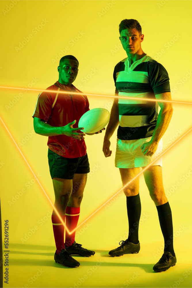 Multiracial male rugby opponents with ball standing by illuminated triangle over yellow background