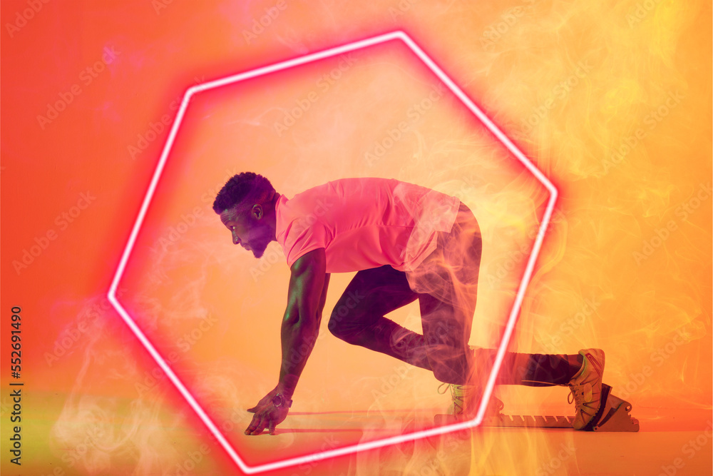 African american male athlete at starting position by illuminated hexagon over gradient background