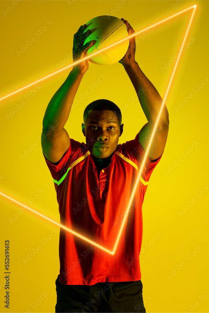 非裔美国男子橄榄球运动员在黄色背景的发光三角形上投球