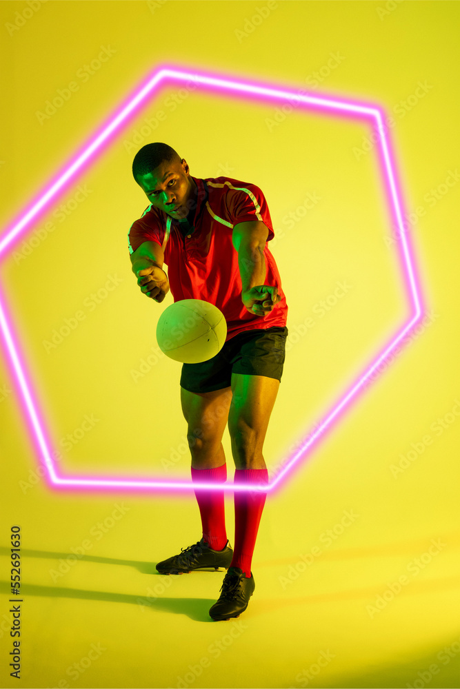 Illuminated hexagon over african american male rugby player throwing ball on green background