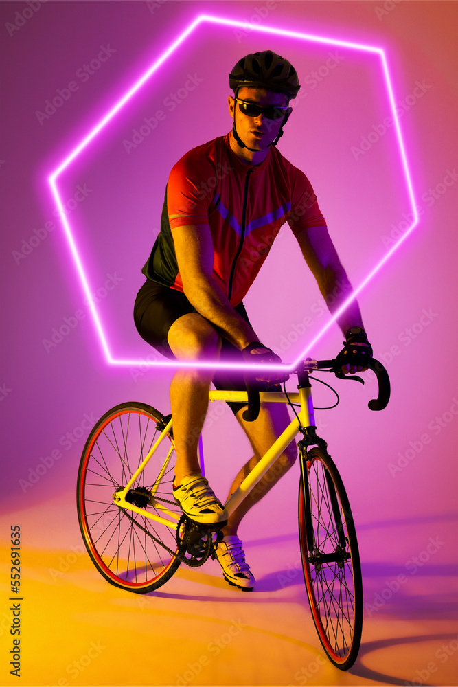 白人男运动员骑自行车越过渐变背景上的照明六边形，复制空间