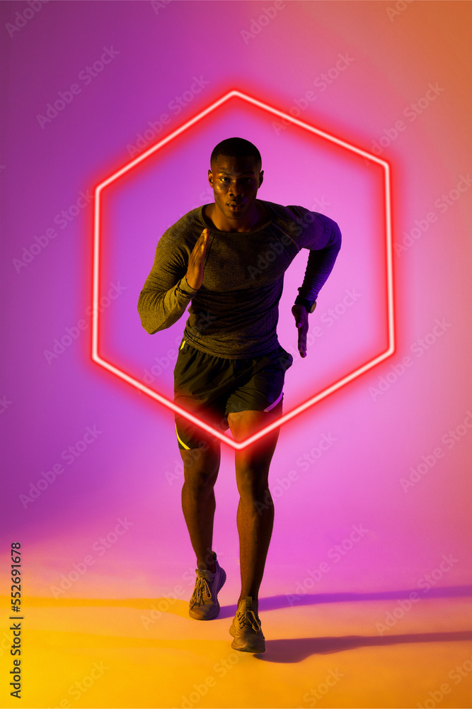 Confident african american male athlete running over illuminated hexagon on gradient background