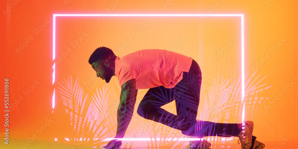 Side view of african american male athlete at starting position by illuminated rectangle and plants