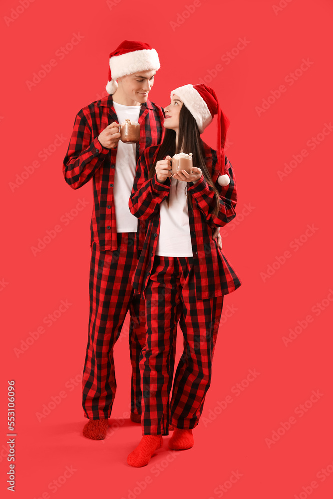 戴着圣诞老人帽的年轻夫妇，红色背景是几杯可可