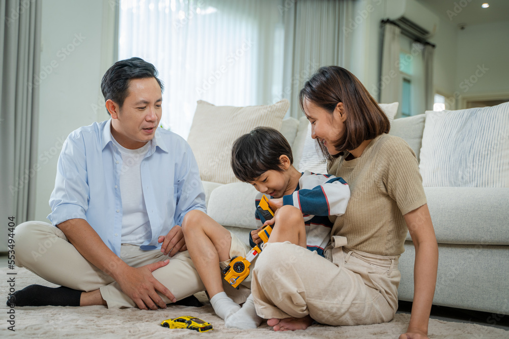 Happy parents playing with son on warm floor in living room,Joyful family enjoying spending weekend 