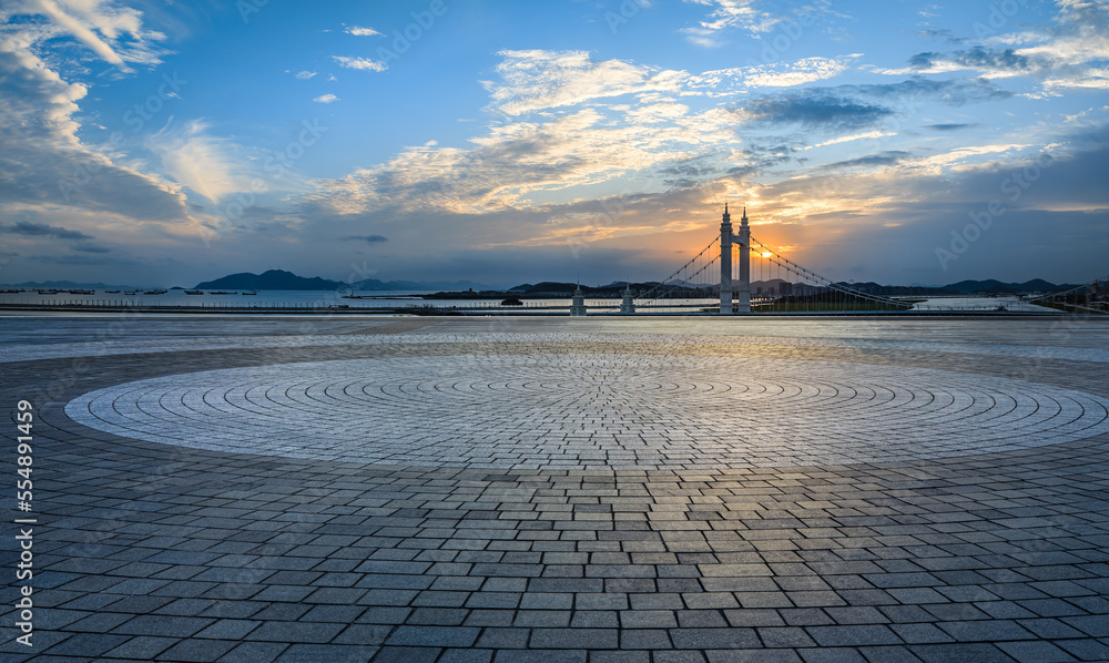 Round city square and bridge with sky clouds at sunset