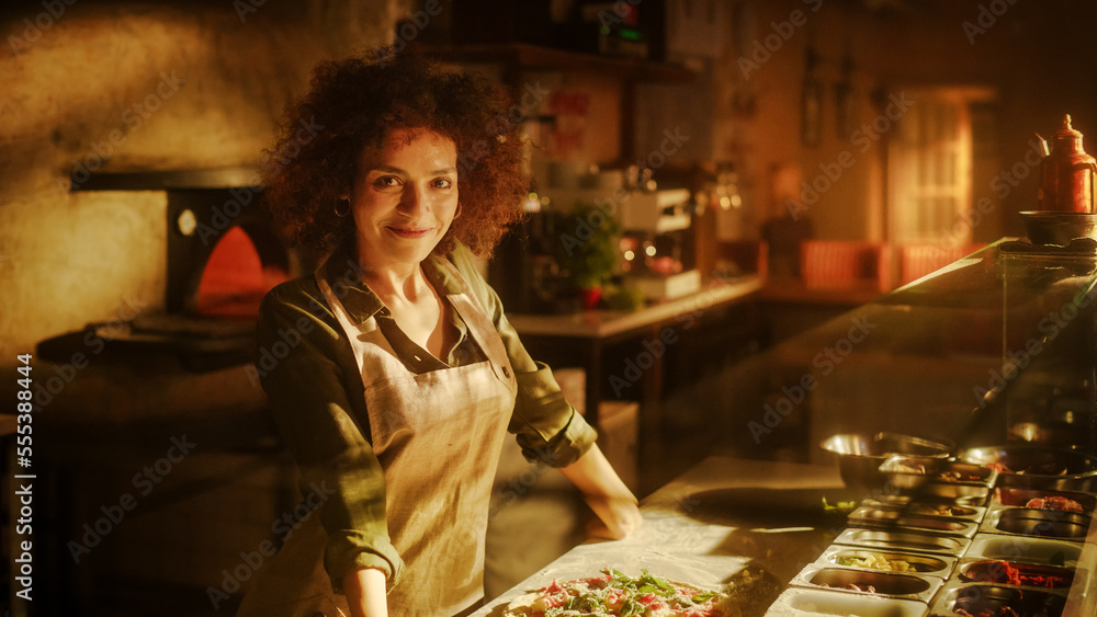 In Restaurant Portrait of Professional Chef Finishing Preparing Pizza, looking at Camera with a Smil