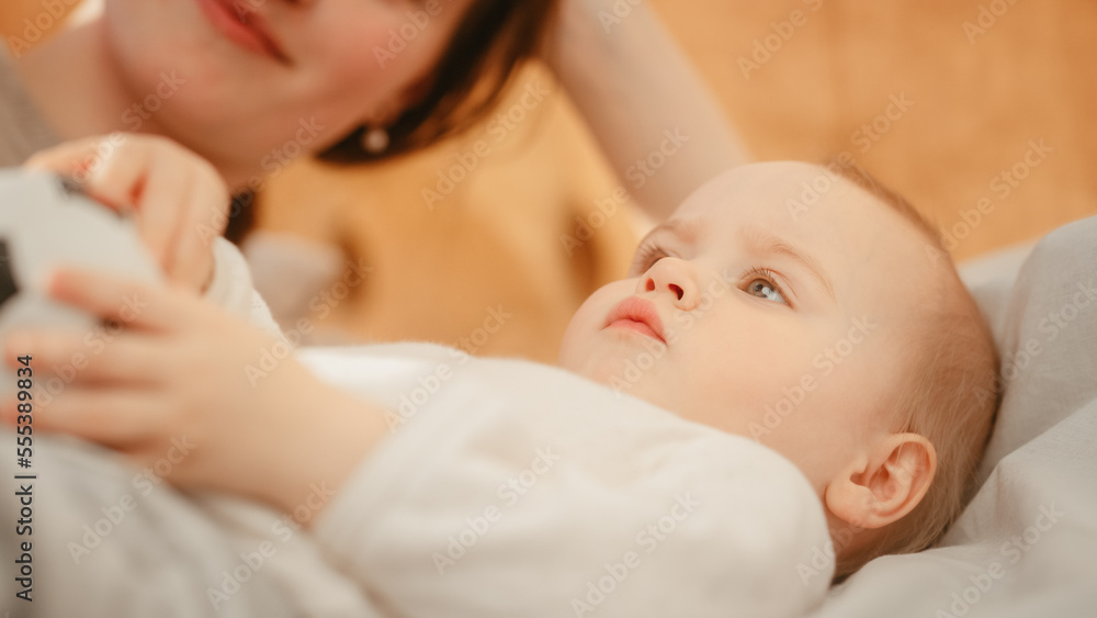 关爱躺在床上的母亲，在家里与可爱的新生儿玩耍。母亲与蹒跚学步的孩子亲密相处，