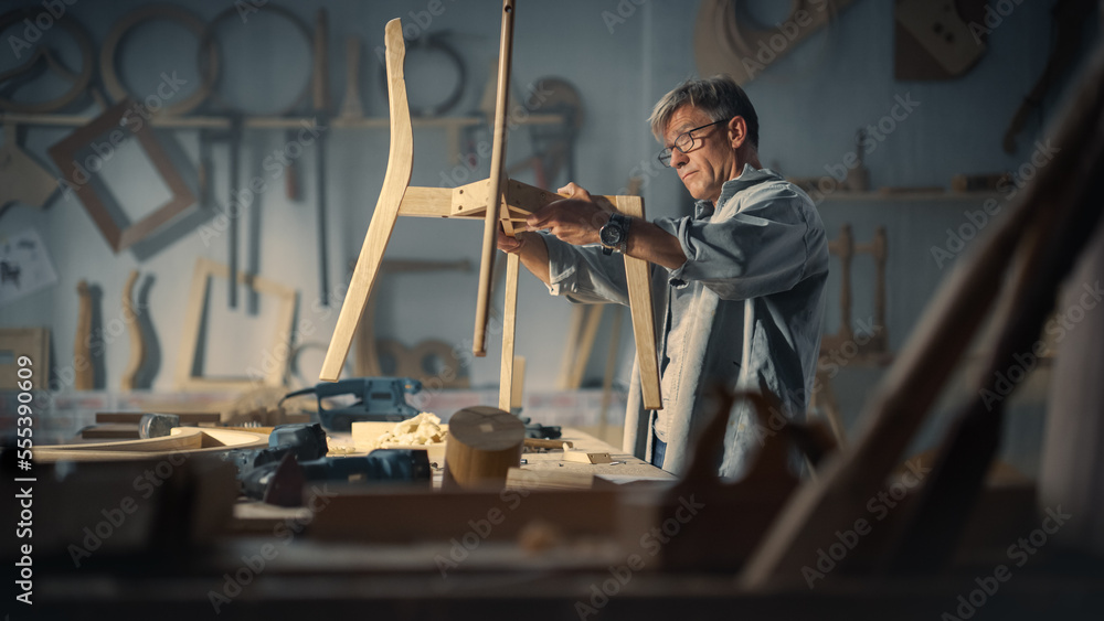 成年木匠戴上眼镜，阅读蓝图，开始组装木制Cha的零件